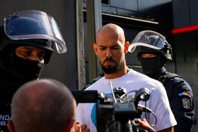 Andrew Tate flanked by masked gendarmes is led for questioning after a police search raid on his residence, on the outskirts of Bucharest, Romania, Wednesday, Aug. 21 2024. Masked police officers in Romania carried out fresh raids early Wednesday at the home of divisive internet influencer Andrew Tate, who is awaiting trial on charges of human trafficking, rape and forming a criminal gang to sexually exploit women. (AP Photo/ Vadim Ghirda).