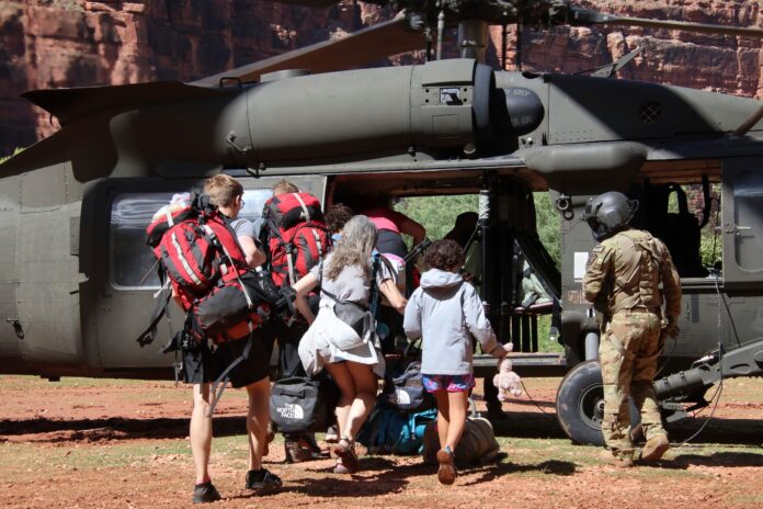 U.S. Army soldiers of the Arizona National Guard guide tourists trapped by flash flooding into a UH-60 Blackhawk, Saturday, Aug. 24, 2024, on the Havasupai Reservation in Supai, Ariz. (Maj. Erin Hannigan/U.S. Army via AP).