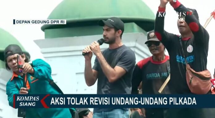 PHOTO: Reza Rahadian giving speech in front of many people at DPR building during shift of election date protest in Indonesia in Depan Gedung DPR RI