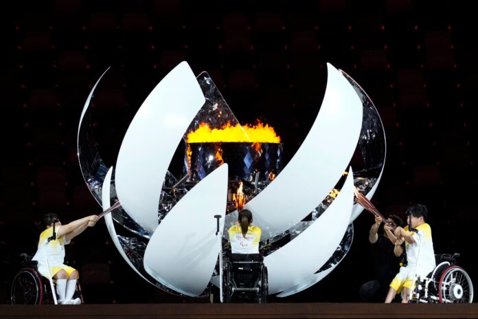 Japan's Yui Kamiji, centre, Shunsuke Uchida, right, and Karin Morisaki light the Paralympic cauldron during the opening ceremony for the 2020 Paralympics at the National Stadium in Tokyo, Aug. 24, 2021. (AP Photo/Shuji Kajiyama).