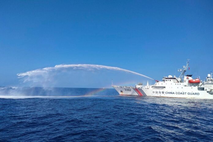 In this photo provided by the Philippine Coast Guard, a Chinese Coast Guard ship, right, uses its water cannons on a Philippine Bureau of Fisheries and Aquatic Resources (BFAR) vessel, as it approaches Scarborough Shoal in the disputed South China Sea, on Dec. 9, 2023. (Philippine Coast Guard via AP, File).