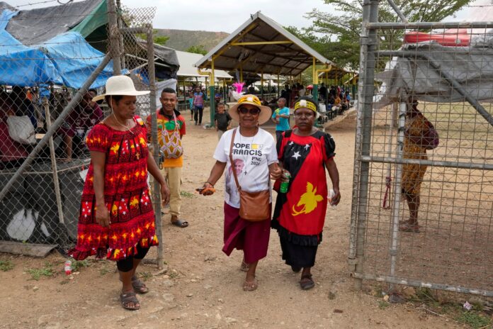 A woman, center, wears a shirt with a photo of Pope Francis at a market ahead of his visit to Port Moresby, Papua New Guinea, Friday, Sept. 6, 2024. (AP Photo/Mark Baker).